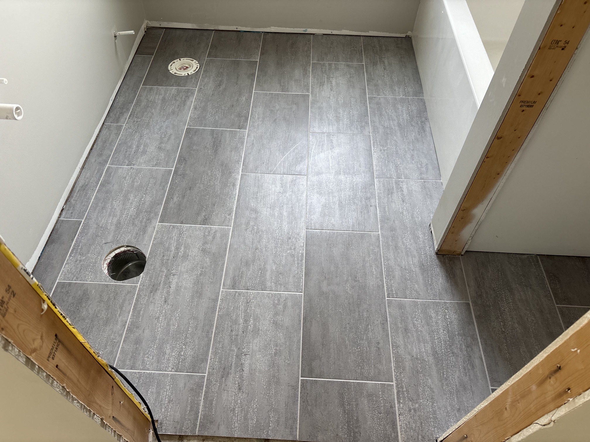 Gray wood-look luxury vinyl plank installed in a bathroom, staggered layout with tight seams